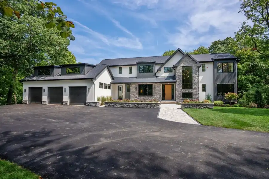 New two-storey home with a stone entry tower, black-framed windows and a three-car garage