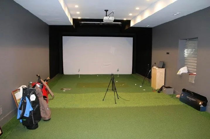 Golf simulator room with turf, a projector and a hitting screen