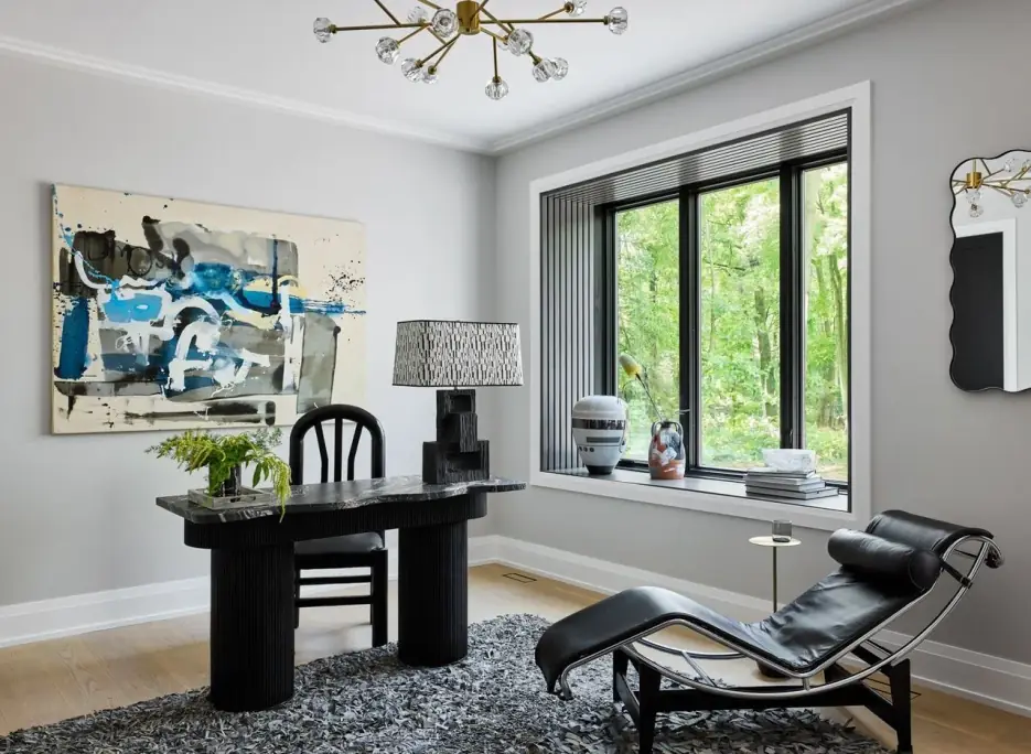 Study with a black desk, lounge chair, large abstract painting and a black-framed window