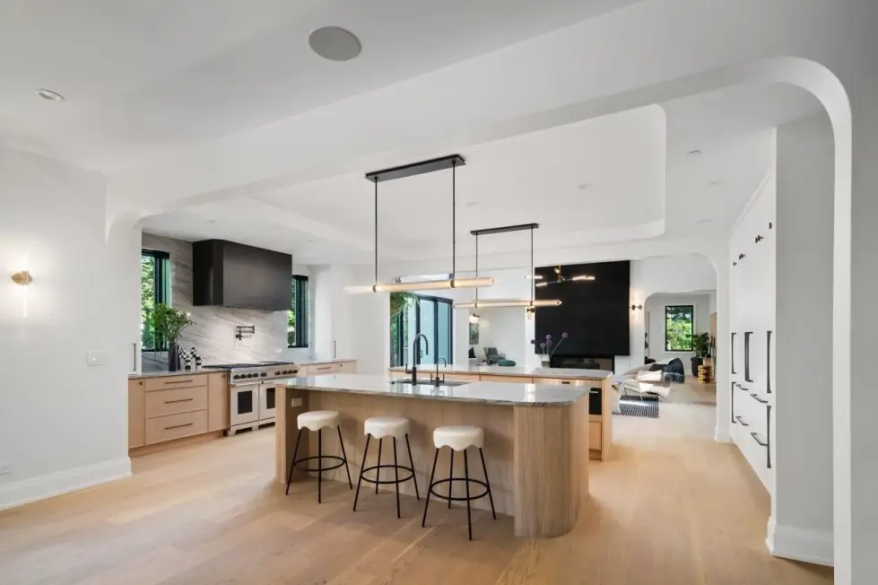 Open kitchen with a stone-topped oak island, a range under a black hood and a bank of oak drawers