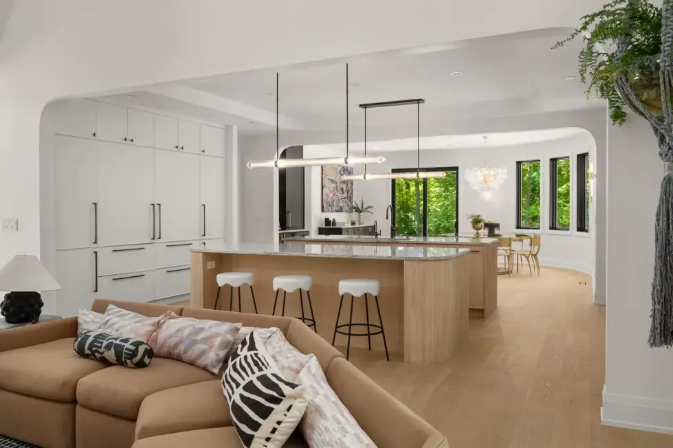 Oak kitchen island with a stone top and stools, open to a family room