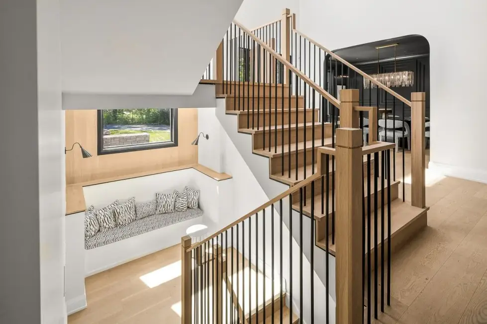 Open stair with white oak treads and rail, black balusters and a window seat under a black-framed window