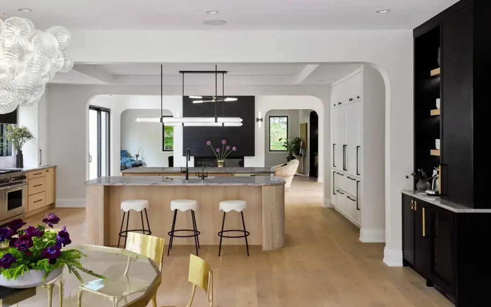Black built-in cabinet beside a pale oak island and wide-plank oak floor